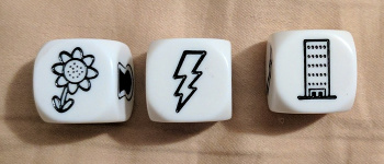 three dice showing a plant, a lightning bolt, and a skyscraper.