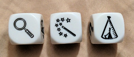 Three dice with pictures of a magnifying glass, a magic wand, and a teepee